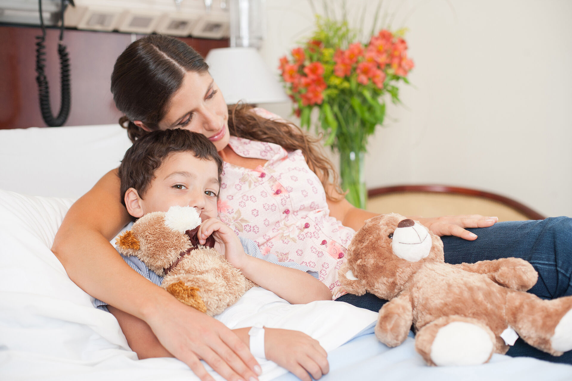 Junge und Frau im Krankenhausbett mit Teddybär
