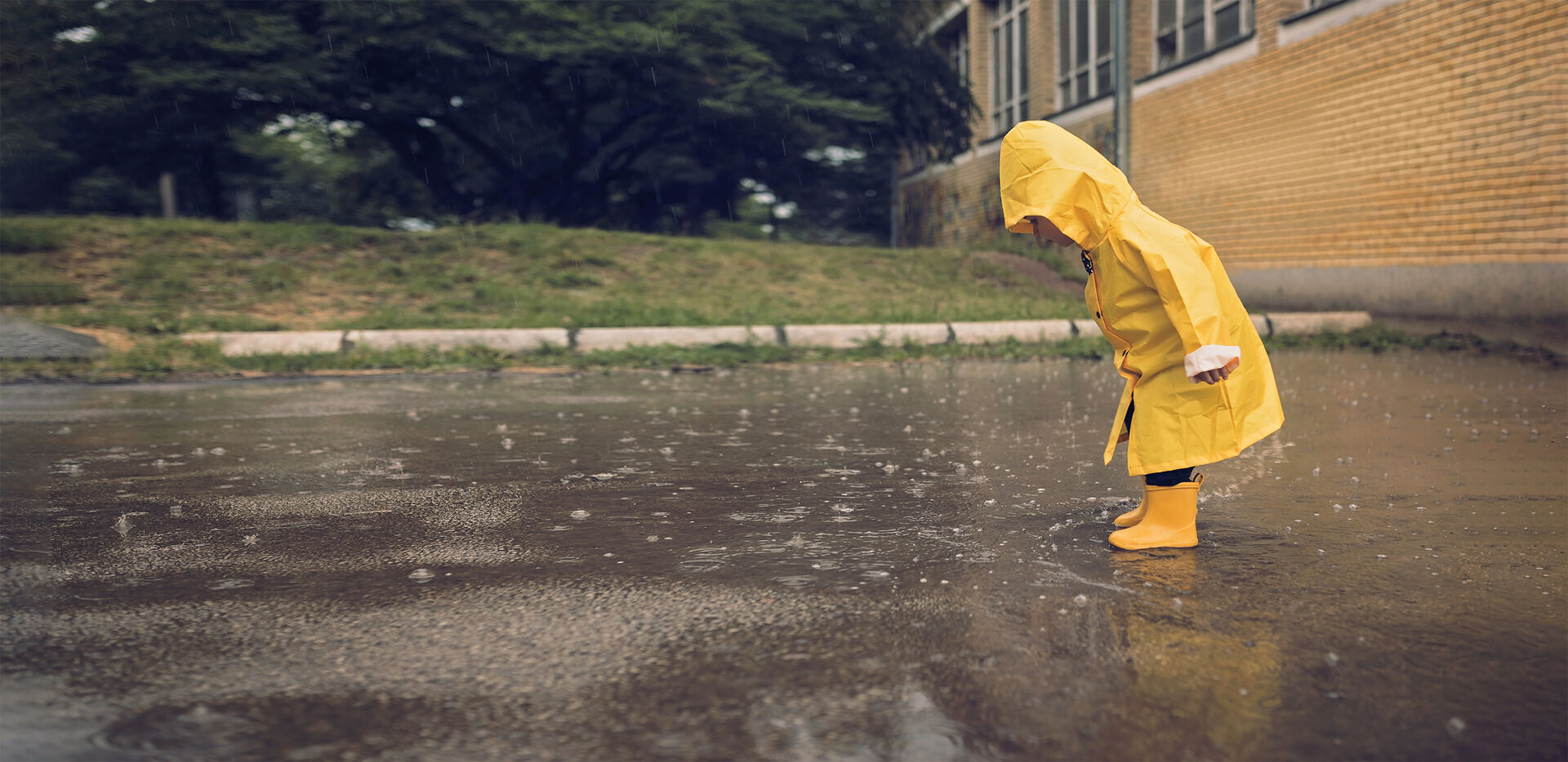 Kleiner Junge spielt bei Regen 