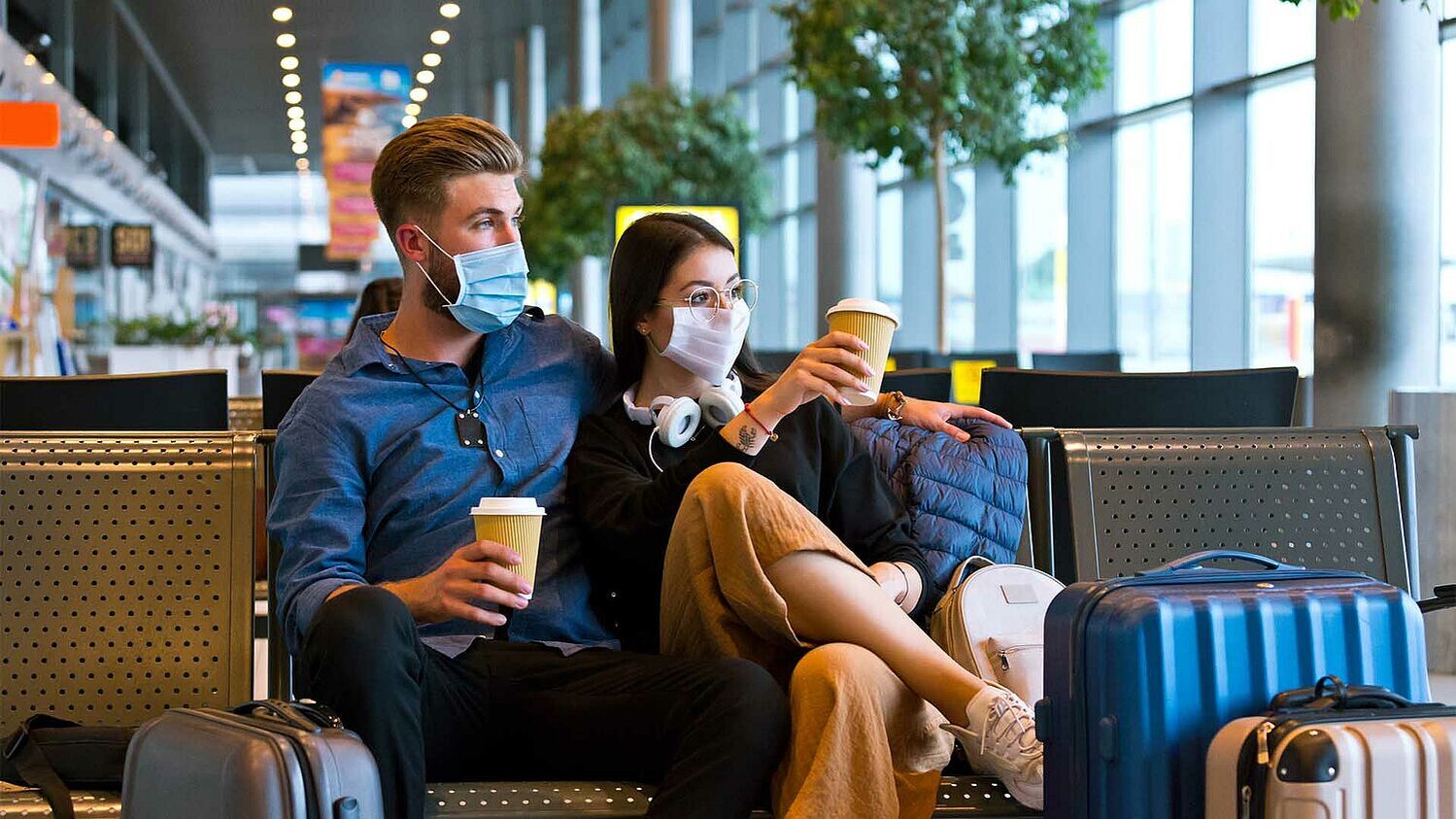 Ein junges Paar sitzt mit ihrem Gepäck im Flughafen-Gate