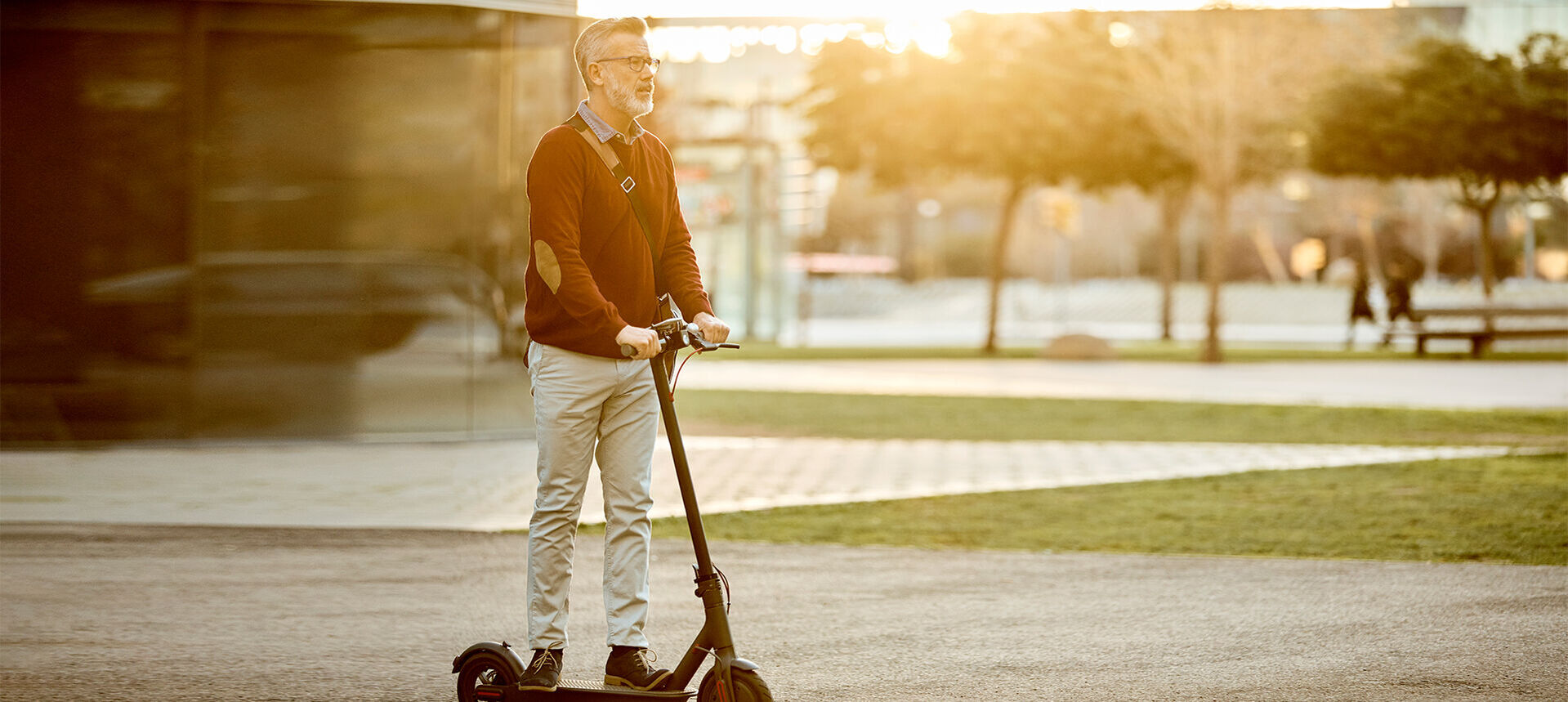 Ein Mann fährt auf einem E-Scooter durch einen Park