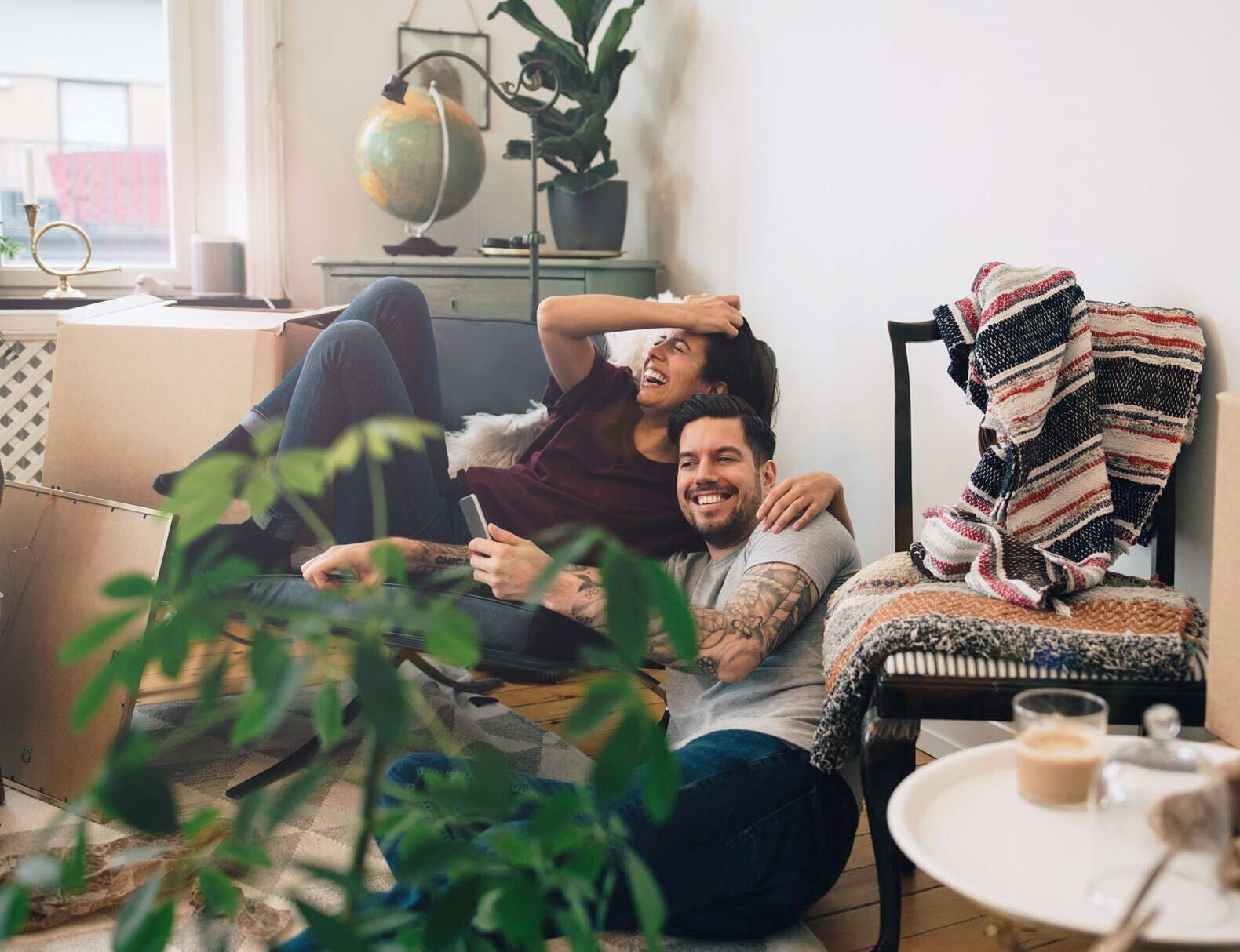 Junges Paar lacht im Wohnzimmer mit Umzugskisten