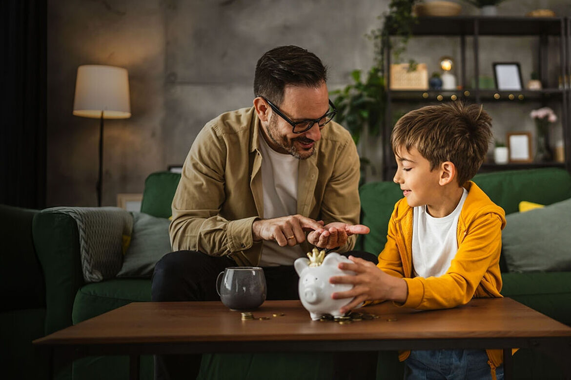 Vater zeigt Sohn, wie man zu Hause im Sparschwein Geld spart
