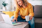 Frau mit Laptop und Kaffeetasse auf dem Sofa