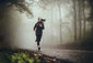 Junge Frau joggt im nebligen Wald