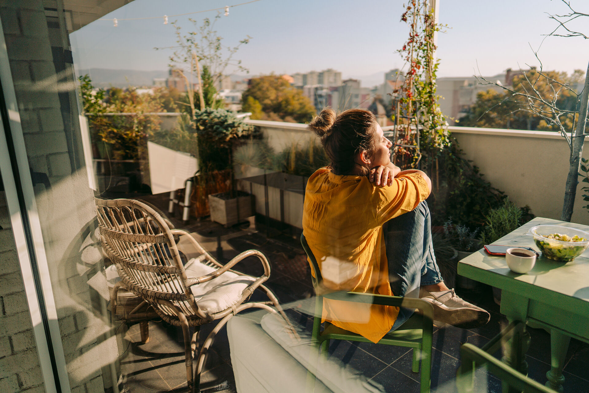 Eine Frau sitzt auf ihrem Balkon und genießt die Sonne
