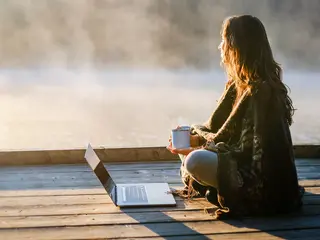 Frau entspannt in Natur mit Laptop