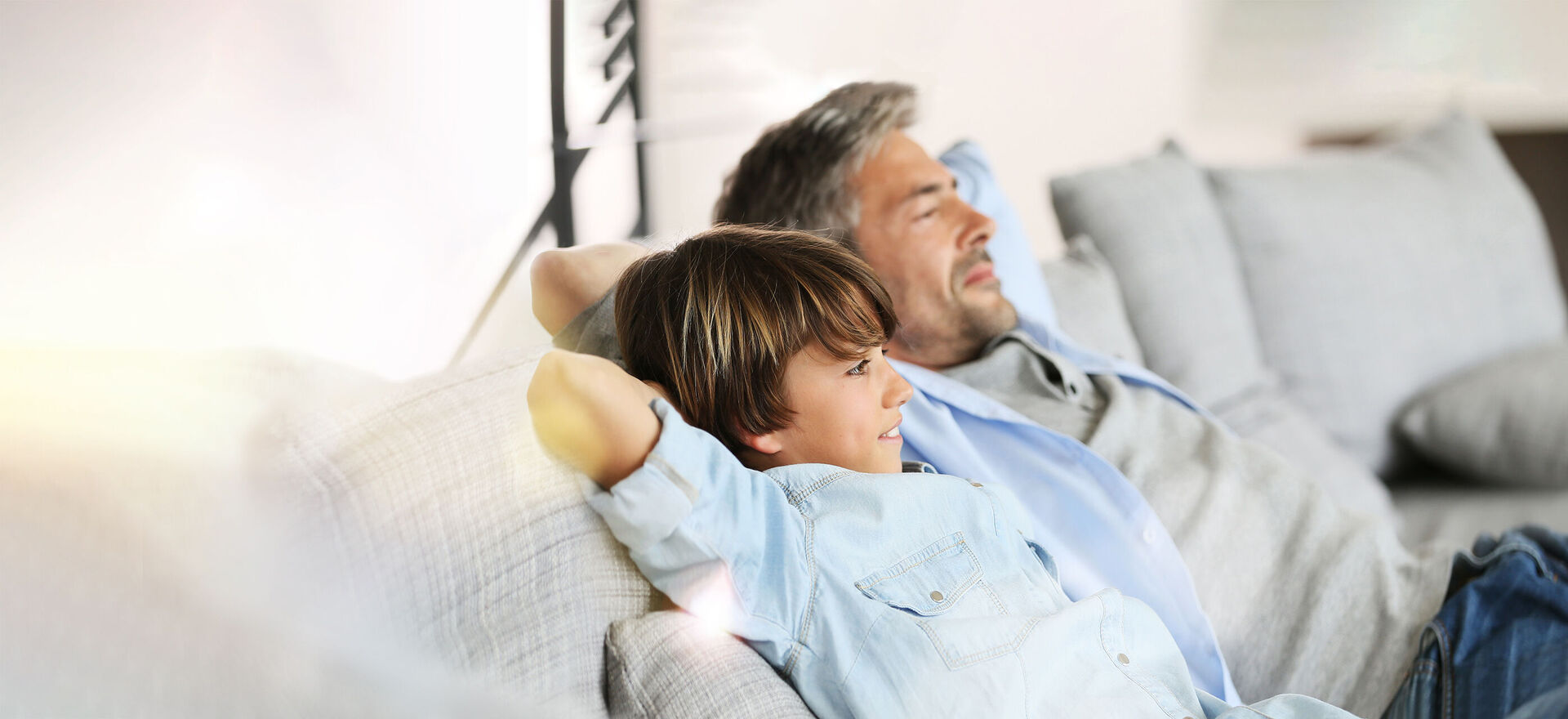 Vater und Sohn liegen entspannt auf der Couch 