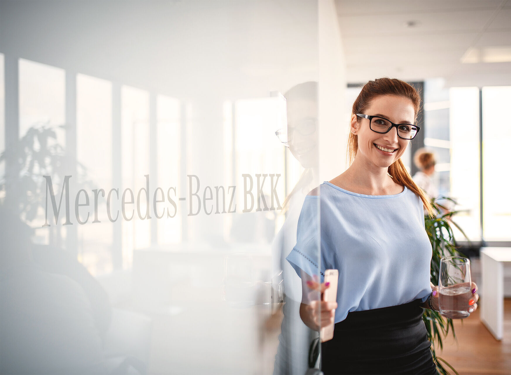 Frau öffnet Bürotür mit Mercedes-Benz BKK Logo