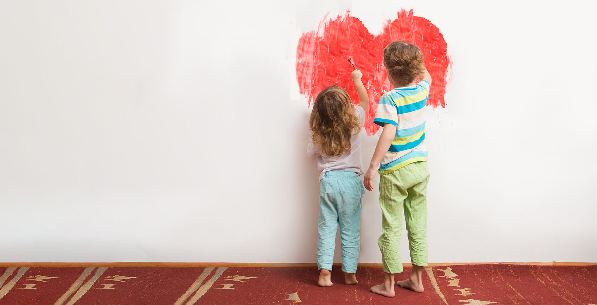 Kinder malen eine Wand rot an